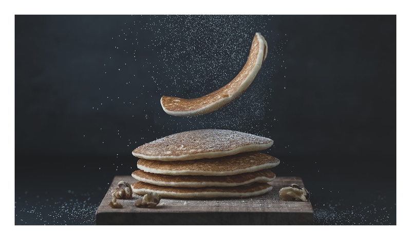 An image of pancakes being plopped down on a wooden cutting board